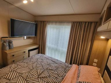 a bedroom with a bed and a television on the wall at Swanage Bay View - Holiday Accommodation 21567 in Swanage