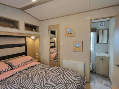 a bedroom with a bed, mirror, and door leading to a bathroom at Swanage Bay View - Holiday Accommodation 21567, Swanage