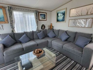 a living room with a gray sectional sofa and a glass coffee table at Swanage Bay View - Holiday Accommodation 21567, Swanage