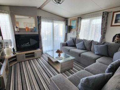 a living room with a sectional sofa, coffee table, and fireplace at Swanage Bay View - Holiday Accommodation 21567, Swanage