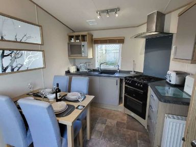 a kitchen with a dining table set for four at Swanage Bay View - Holiday Accommodation 21567, Swanage