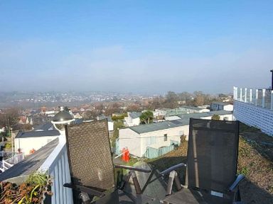 a view from a terrace showing two chairs overlooking houses and a landscape at Swanage Bay View - Holiday Accommodation 21567, Swanage
