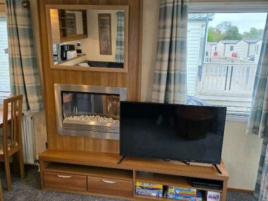 a living room with a wall-mounted TV, electric fireplace, and a mirror at Beacon Fell View Holiday Park - Holiday Accommodation 21653, Preston