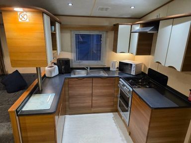 a kitchen with wooden cabinets, a sink, stove, and appliances at Beacon Fell View Holiday Park - Holiday Accommodation 21653, Preston