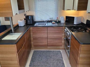 a kitchen with wooden cabinets, a sink, and appliances at Beacon Fell View Holiday Park - Holiday Accommodation 21653, Preston