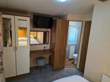 a room with a wardrobe, a desk with a stool, and an en-suite bathroom at Beacon Fell View Holiday Park - Holiday Accommodation 21653, Preston