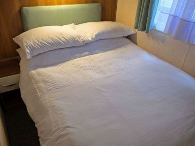 a double bed with white bedding and a headboard in a room at Beacon Fell View Holiday Park - Holiday Accommodation 21653, Preston