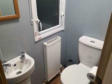a bathroom with a toilet, sink, radiator, and window at Beacon Fell View Holiday Park - Holiday Accommodation 21653, Preston