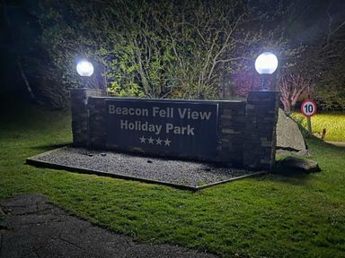 a sign for Beacon Fell View Holiday Park with lights at night in Preston