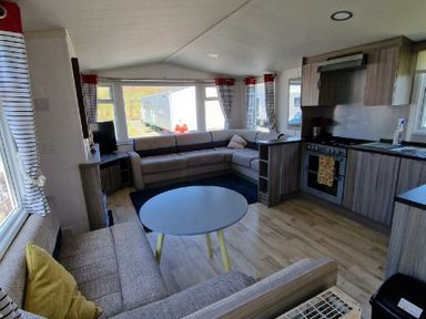 a living room with a sofa, coffee table, and kitchen area at Clarach Bay Holiday Village - Holiday Accommodation 21674 in Aberystwyth