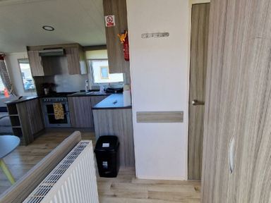 a kitchen area with cabinets, a stove, and a door leading to another room at Clarach Bay Holiday Village - Holiday Accommodation 21674, Aberystwyth