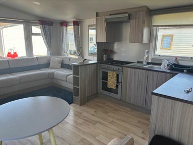 a kitchen area with a sofa and dining table at Clarach Bay Holiday Village - Holiday Accommodation 21674 in Aberystwyth