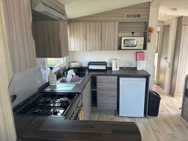 a kitchen with cabinets, a stove, microwave, and refrigerator at Clarach Bay Holiday Village - Holiday Accommodation 21674, Aberystwyth