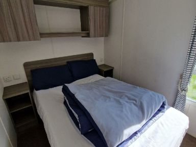 a bedroom with a double bed and shelves at Clarach Bay Holiday Village - Holiday Accommodation 21674, Aberystwyth