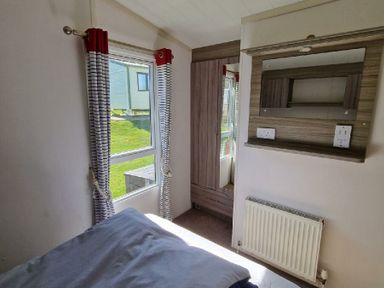 a room with a window, a wardrobe, and a wall-mounted shelf at Clarach Bay Holiday Village - Holiday Accommodation 21674 Aberystwyth