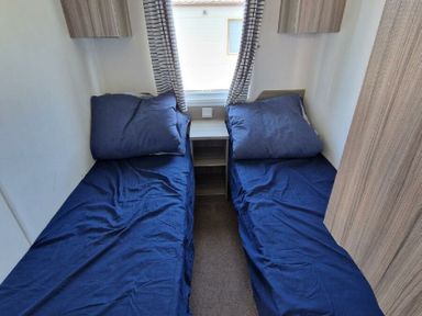 a room with two single beds and a bedside table at Clarach Bay Holiday Village - Holiday Accommodation 21674 in Aberystwyth