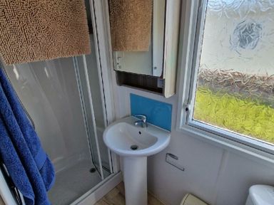 a bathroom with a shower, sink, and mirror at Clarach Bay Holiday Village - Holiday Accommodation 21674, Aberystwyth