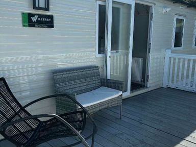 a seating area with wicker chairs and a door at Brynowen Holiday Park - Holiday Accommodation 21677, Borth, Aberystwyth