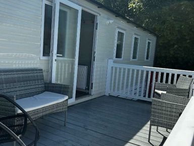 a deck with seating and a door leading to a room at Brynowen Holiday Park - Holiday Accommodation 21677, Borth, Aberystwyth
