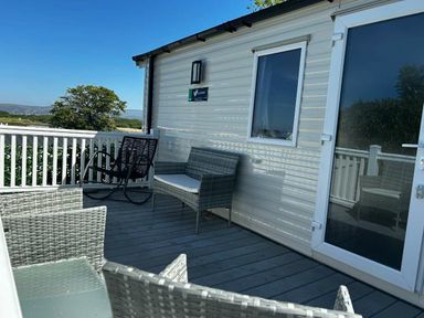 a deck area with wicker furniture and a view at Brynowen Holiday Park - Holiday Accommodation 21677 Borth, Aberystwyth