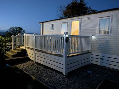 a white mobile home with a wooden deck and steps at Brynowen Holiday Park - Holiday Accommodation 21677 in Borth, Aberystwyth
