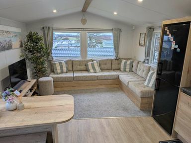 a living room with a sectional sofa, coffee table, and TV at Brynowen Holiday Park - Holiday Accommodation 21677, Borth, Aberystwyth