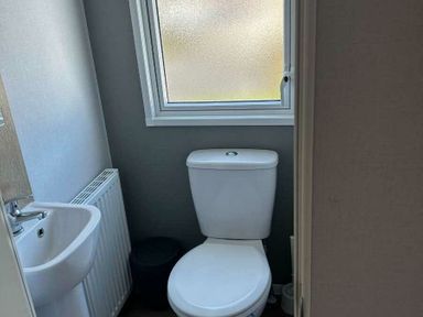 a bathroom with a toilet, sink, and window at Brynowen Holiday Park - Holiday Accommodation 21677, Borth, Aberystwyth