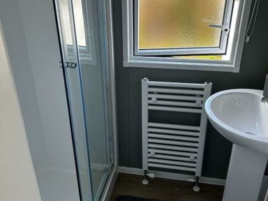 a bathroom with a shower stall, sink, and a towel radiator at Brynowen Holiday Park - Holiday Accommodation 21677, Borth, Aberystwyth