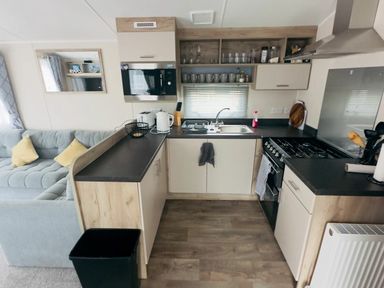 a kitchen with cabinets, a sink, microwave, and stove at Lido Beach Holiday Park - Holiday Accommodation 21682, Prestatyn