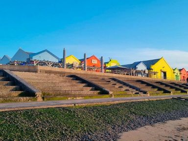 a row of colorful beach huts on a promenade with steps leading down at Lido Beach Holiday Park - Holiday Accommodation 21682 Prestatyn