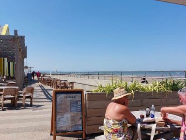 a beachfront area with tables and chairs at Lido Beach Holiday Park - Holiday Accommodation 21682 in Prestatyn