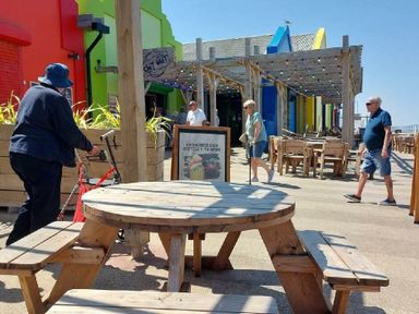 an outdoor dining area with colorful buildings and people walking at Lido Beach Holiday Park - Holiday Accommodation 21682, Prestatyn