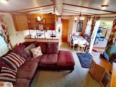 a living room area with a sectional sofa and dining table at Hafan y Mor Haven - Holiday Accommodation 21715 Pwllheli