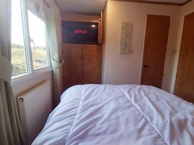 a bedroom with a bed and TV displaying Netflix at Hafan y Mor Haven - Holiday Accommodation 21715, Pwllheli