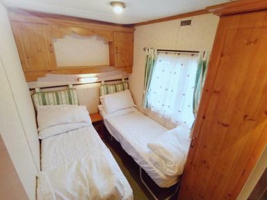 a bedroom with two beds and wooden furniture at Hafan y Mor Haven - Holiday Accommodation 21715, Pwllheli