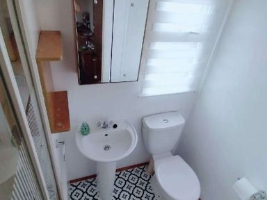 a bathroom with a toilet, sink, and mirror at Hafan y Mor Haven - Holiday Accommodation 21715 Pwllheli