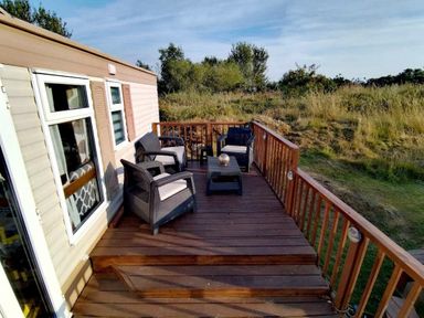 a wooden deck with outdoor furniture at Hafan y Mor Haven - Holiday Accommodation 21715 Pwllheli