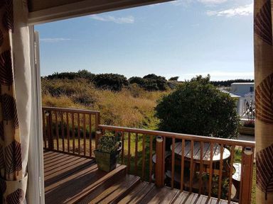 a view of grass and shrubs from a deck at Hafan y Mor Haven - Holiday Accommodation 21715 Pwllheli