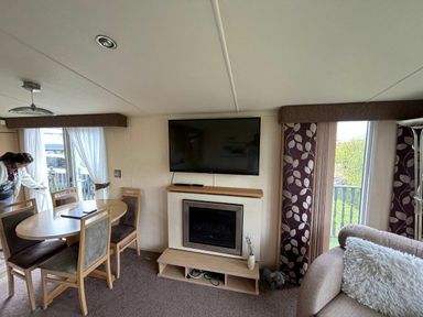 a living room with a dining table and a television at Clarach Bay Holiday Village - Holiday Accommodation 21850 Aberystwyth
