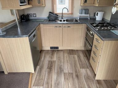 a kitchen with wooden cabinets and stainless steel appliances at Clarach Bay Holiday Village - Holiday Accommodation 21850, Aberystwyth