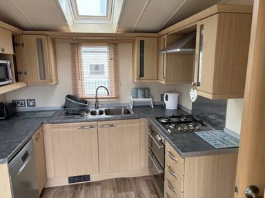 a kitchen with wooden cabinets and stainless steel appliances at Clarach Bay Holiday Village - Holiday Accommodation 21850 Aberystwyth
