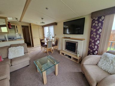 a living room with a television, coffee table, and dining area at Clarach Bay Holiday Village - Holiday Accommodation 21850 Aberystwyth