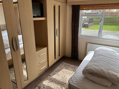 a bedroom with a wardrobe, a bed, and a window at Clarach Bay Holiday Village - Holiday Accommodation 21850 in Aberystwyth