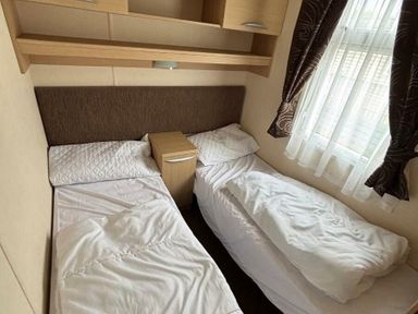 a bedroom with two single beds and a bedside table at Clarach Bay Holiday Village - Holiday Accommodation 21850, Aberystwyth