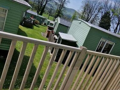a view of several green cabins in a grassy area at Woodlands Holiday Park - Holiday Accommodation 21859 in Twywn