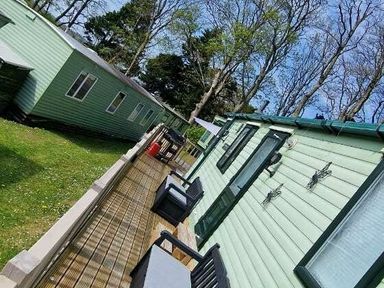 a row of holiday cabins with a walkway and outdoor seating at Woodlands Holiday Park - Holiday Accommodation 21859 in Twywn