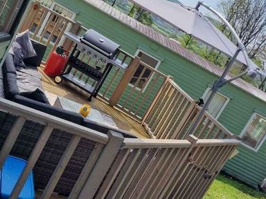 a deck area with a grill and seating located at Woodlands Holiday Park - Holiday Accommodation 21859 in Twywn