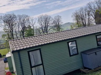 a cabin with a pitched roof and a storage box outside at Woodlands Holiday Park - Holiday Accommodation 21859 in Twywn