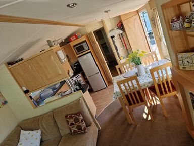 a kitchen and dining area with a table and chairs at Woodlands Holiday Park - Holiday Accommodation 21859, Twywn