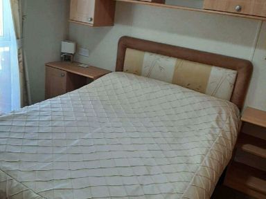 a bedroom with a double bed and a wooden bedside table at Woodlands Holiday Park - Holiday Accommodation 21859 in Twywn